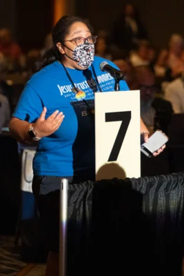 A woman stands behind a microphone.
