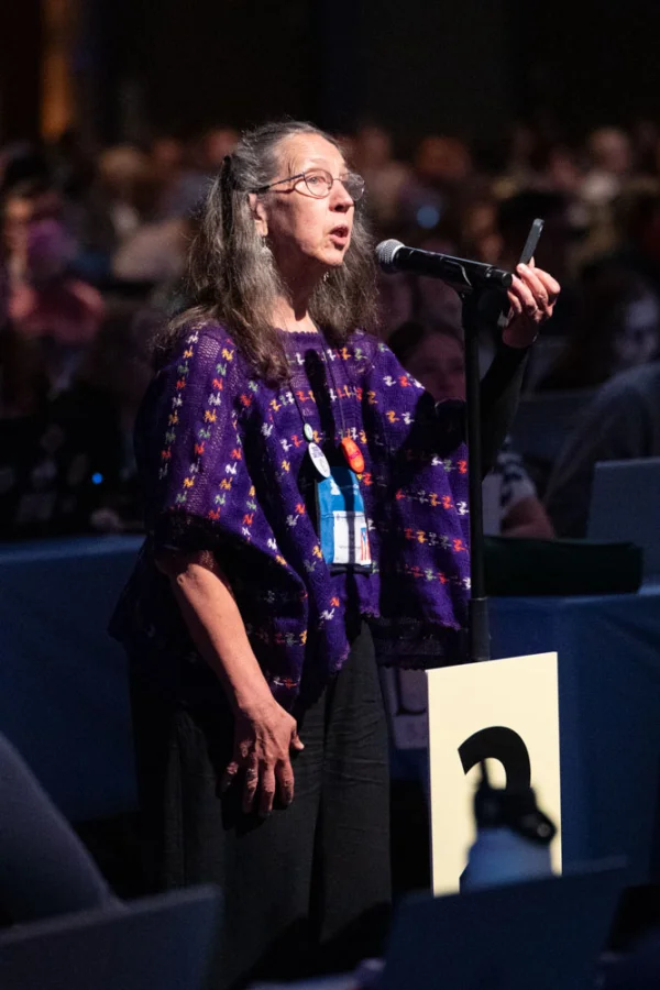 A woman stands at a microphone.