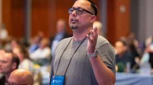 A man speaks to a crowd, moving his hands.
