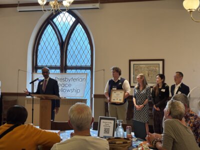 Vince Thomas standing at a microphone, speaking and accepting the 2026 Peacekeeper Award