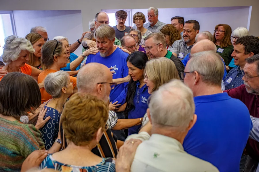 A group of people lay hands on Mark Adams and Miriam Maldonado.