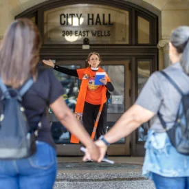 In the foreground, two women stand hand in hand. In the background, Margery Rossi, coordinator of gun violence prevention with the Presbyterian Peace Fellowship leads prayer.