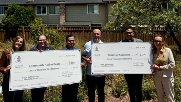 A group of people hold two large checks