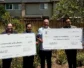 A group of people hold two large checks