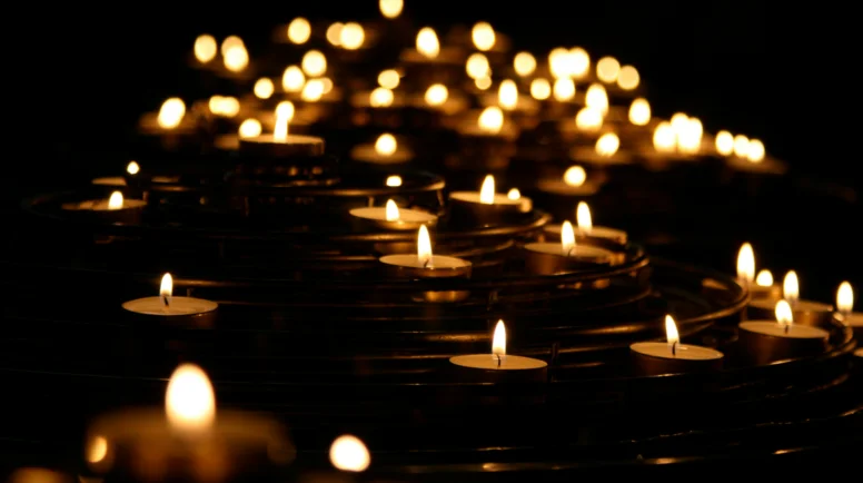 A series of small tealights lit up in front of a dark background.