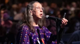 A woman stands at a microphone.