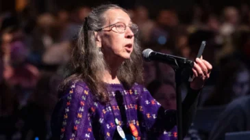 A woman stands at a microphone.