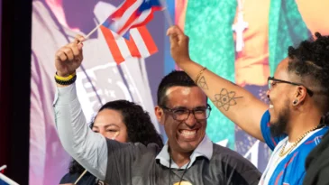 A group of people smile and hold Puerto Rican flags
