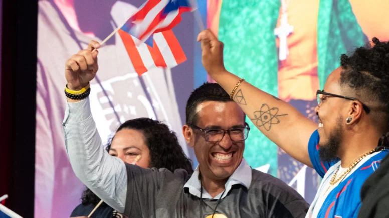A group of people smile and hold Puerto Rican flags