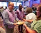 Two volunteers in purple vests offer bread and grape juice for communion.