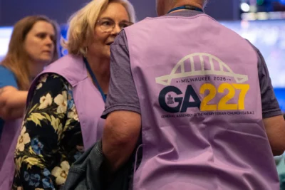Two volunteers in purple vests talk to one another.