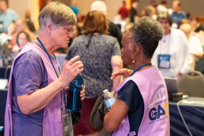 Two volunteers in purple vests talk to one another.