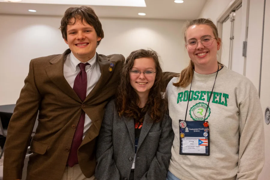 Three young adults smile and pose for a picture.