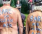 Two participating of the Naked Bike Ride with painted backs stating "Bare for Clean Air"
