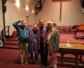 Four people with ashes on their foreheads take a picture in a church's sanctuary
