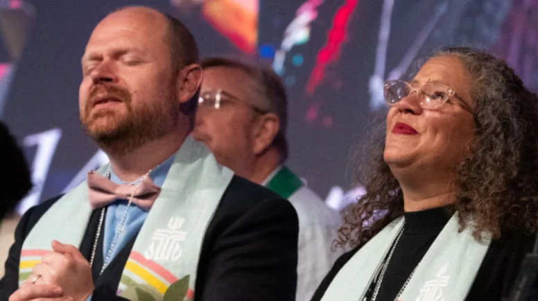 The Rev. Marta Pumroy-Cordero and the Rev. Dr. Kristopher D. Schondelmeyer worship next to each other on the stage of GA227.