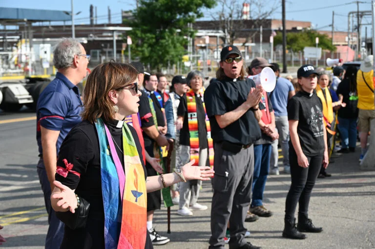 Clergy in stoles and collars stand outside