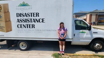 Emily Hooker stands in front of a box truck that has Fernclif's logo and the words "Disaster Assistant Center"