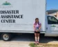Emily Hooker stands in front of a box truck that has Fernclif's logo and the words "Disaster Assistant Center"