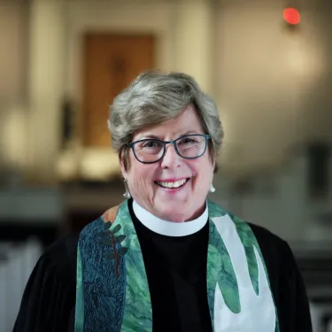Joanna Adams smiles at the camera wearing black preaching robes and a stole.