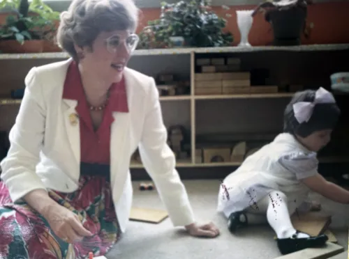 Joanna Adams sits on the floor next to a child.
