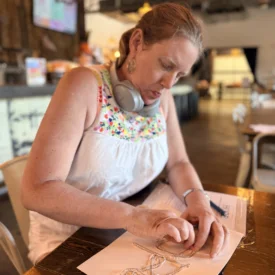 Eleanor Shell, founder of Borrowed Hope, sits at a table and draws.