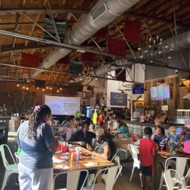 A group of people talk and gather around tables at Borrowed Hope's June 11, 2026 event.