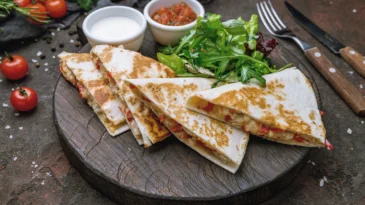 Quesadilla with chicken and sauces on dark board , on dark rustic concrete background