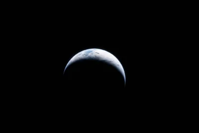 Space image of earth with a crescent shape of light shining on the top