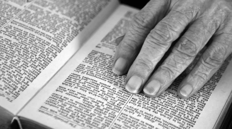 Black and white photo of a hand resting on a Bible