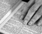 Black and white photo of a hand resting on a Bible