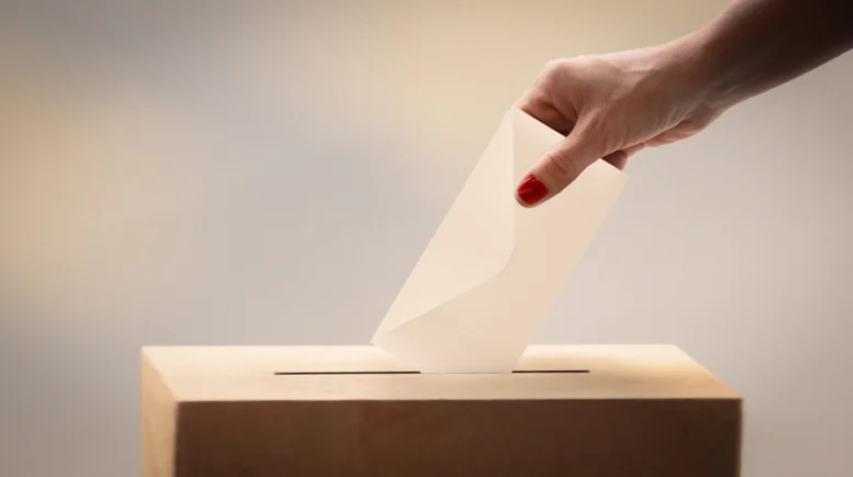 Female voter placing her ballot at the ballot box