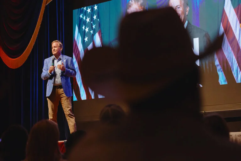 Republican candidate for U.S. Senate and state Attorney General Ken Paxton stands on stage holding a microphone.