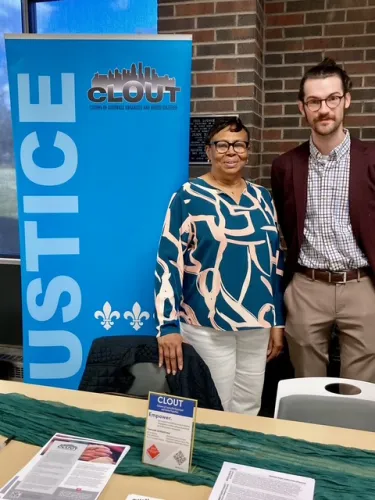 Two people stand by a Citizens of Louisville Organized and United Together (CLOUT) sign