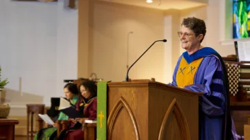 Union Presbyterian Seminary President Jacqueline Lapsley stands behind a podium in academic robes.