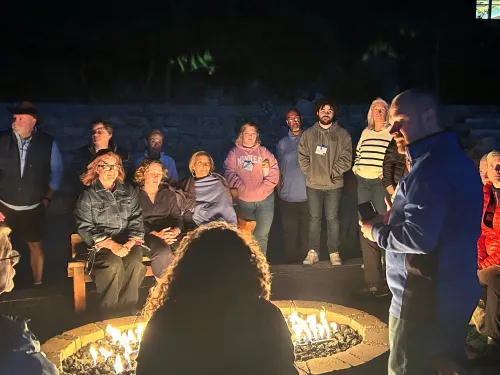 People gather around a fire outside. 