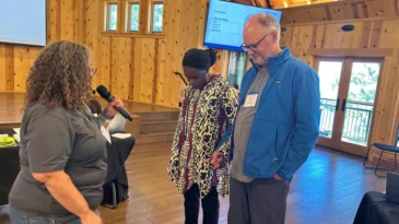 The Rev. Marta Pumroy-Cordero stands before Board Co-Chairs Aleathea Harris-Little & the Rev. Scott Lumsden