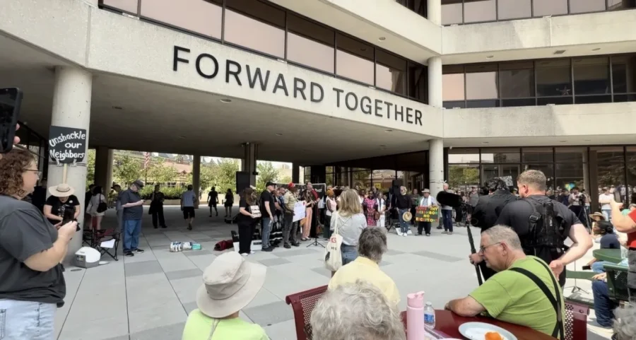 A group of people gather outside under a sign that reads "forward together"