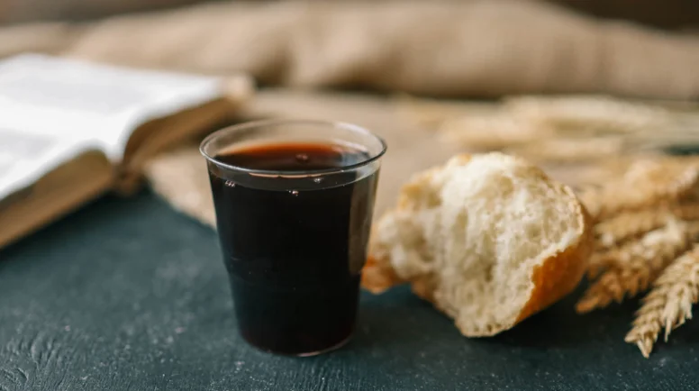 Cup with wine, bread and open Bible, Christian communion.