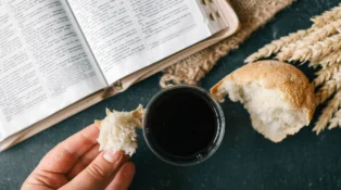 Cup with wine, bread and open Bible, Christian communion.