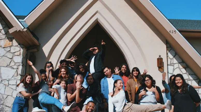 A group of young adults posing in front of a church building.