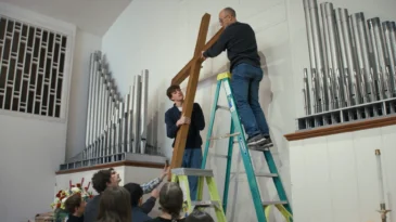 Church members at Christ Congregational Church remove the cross from the sanctuary to put in storage after selling their building. (Photo by Journey Films)