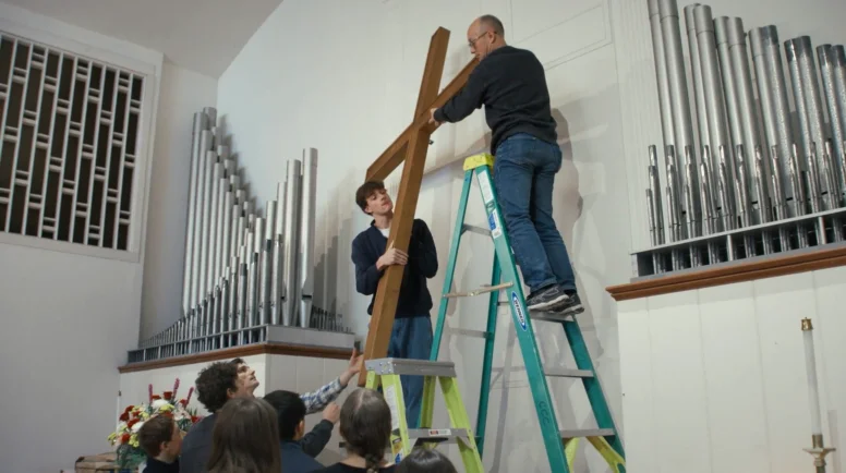Church members at Christ Congregational Church remove the cross from the sanctuary to put in storage after selling their building. (Photo by Journey Films)